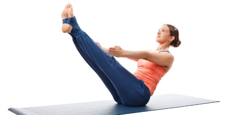 woman practices paripurna navasana boat pose in yoga