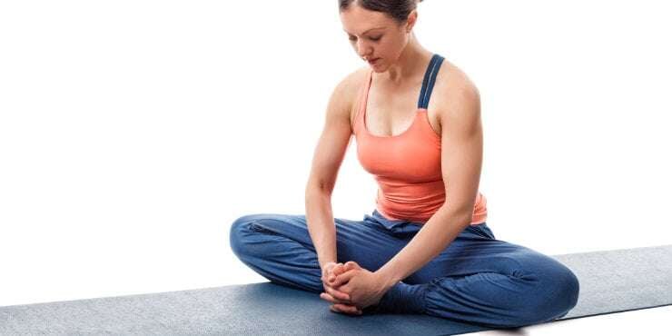 bound angle pose woman practices yoga asana baddha konasana