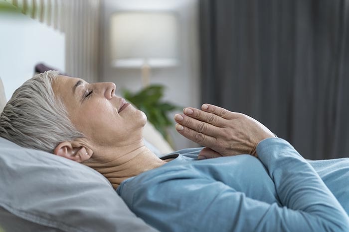 donna che pratica la meditazione guidata per il sonno sdraiata a letto
