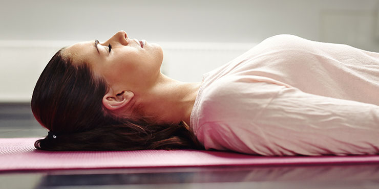 donna sdraiata sul tappetino da yoga che rilassa i muscoli facendo meditazione sul sonno